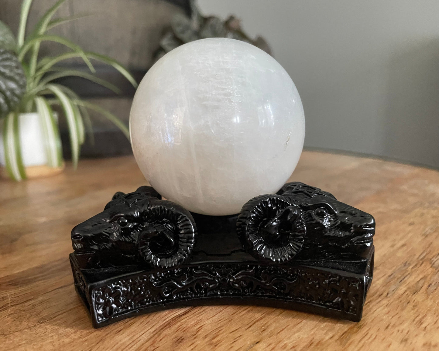 Pictured is a sphere stand in the shape of three ram skulls or goat skulls.