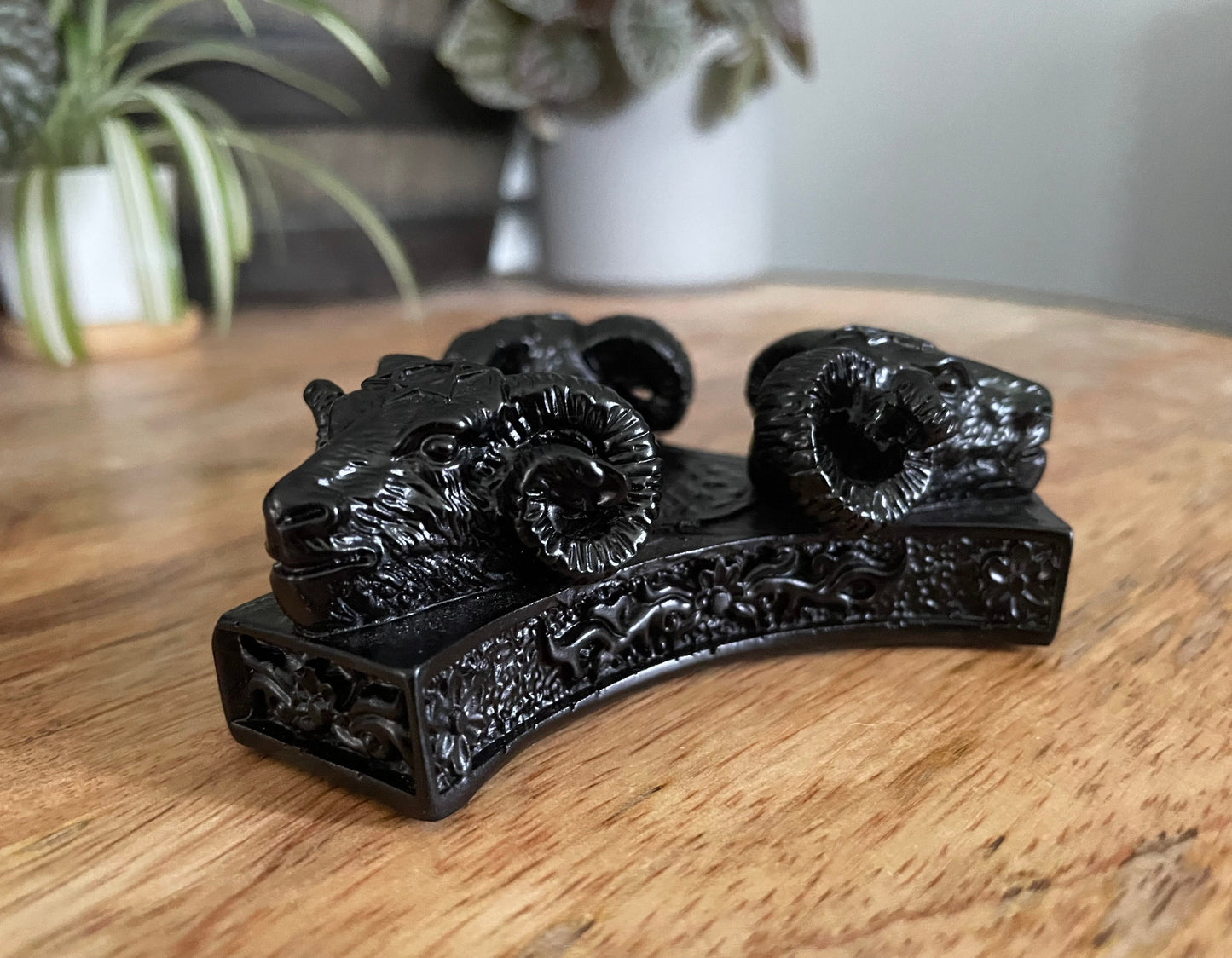 Pictured is a sphere stand in the shape of three ram skulls or goat skulls.