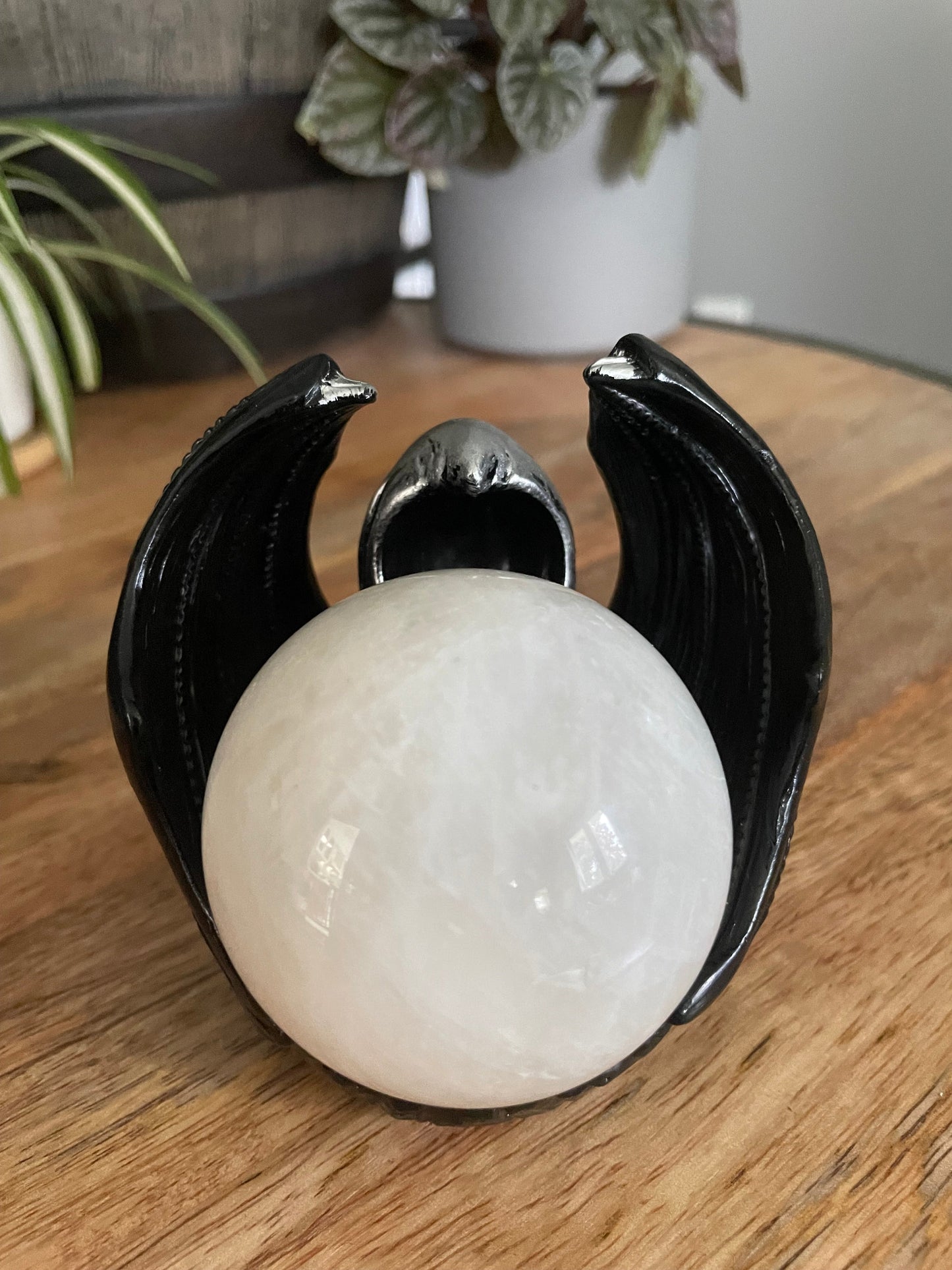 Pictured is a sphere stand in the shape of a hooded figure with dragon wings. Masked Dragon Crystal Sphere Stand example