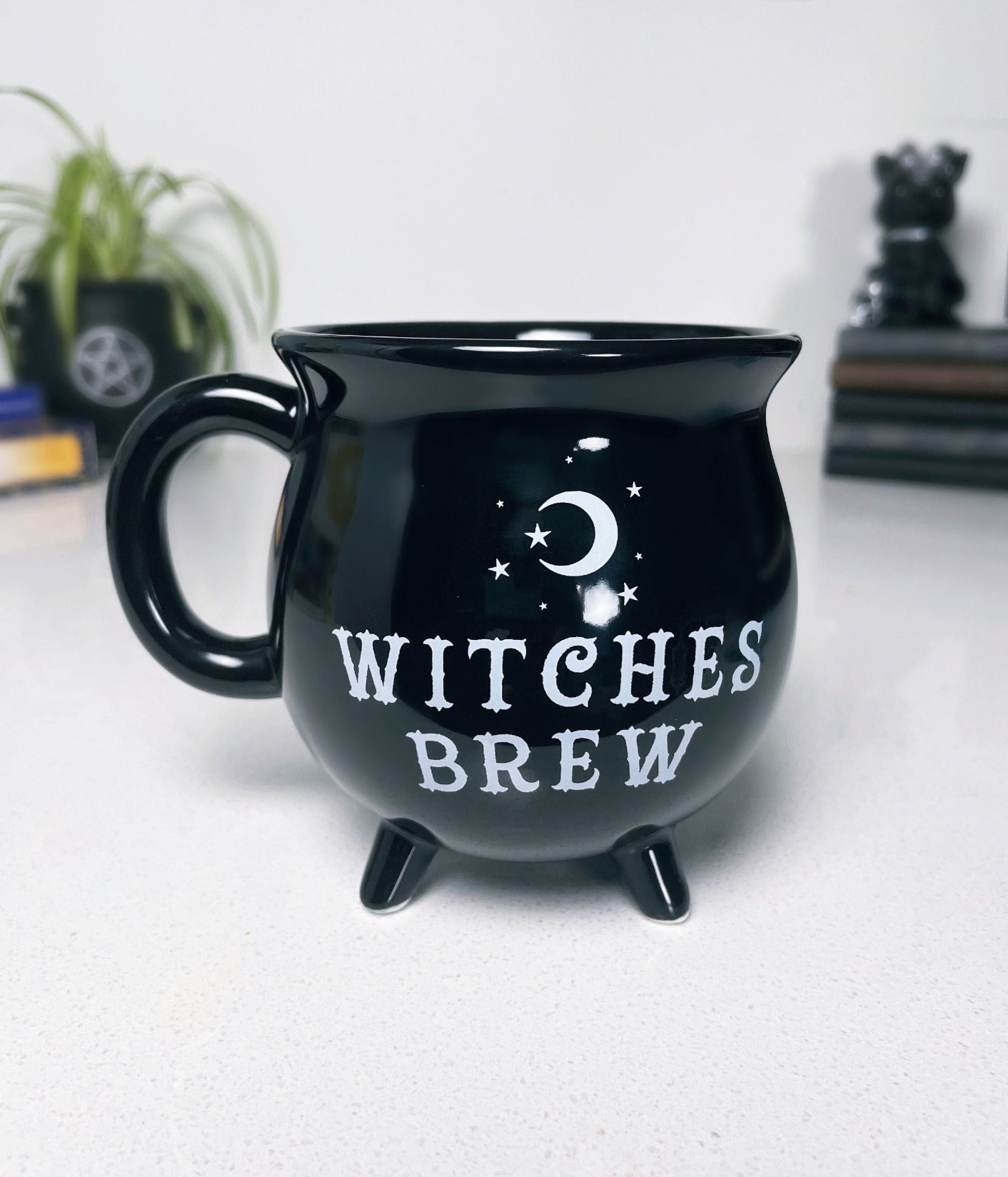 A black ceramic cauldron-shaped mug with a white label that says "Witches Brew" on the side. "Witches Brew" Cauldron Ceramic Mug