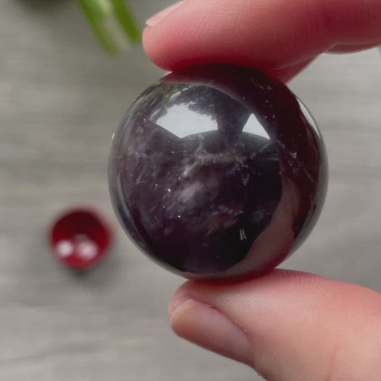 A polished sphere of amethyst is shown in the image. The crystal is a purple color and has a smooth, shiny surface. Amethyst Crystal Sphere 31mm (B) video