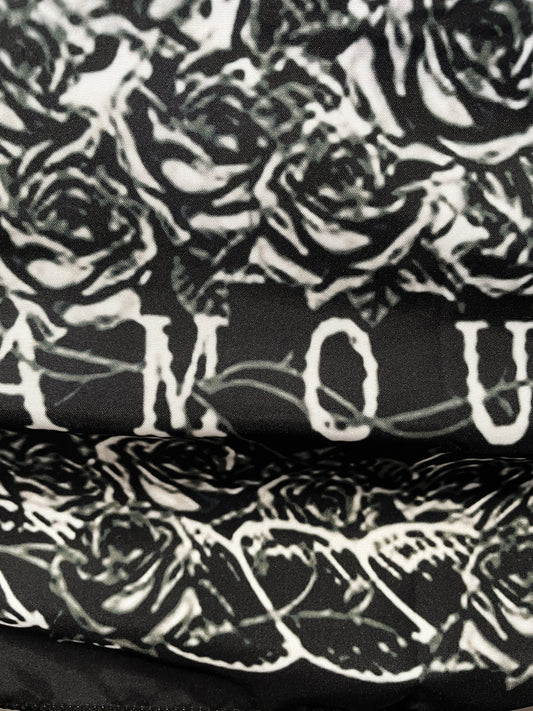 Pictured is a large wall tapestry with a black background and two skeletons kissing on a tarot card "the lovers" printed in white on it. The Lovers Wall Tapestry close up